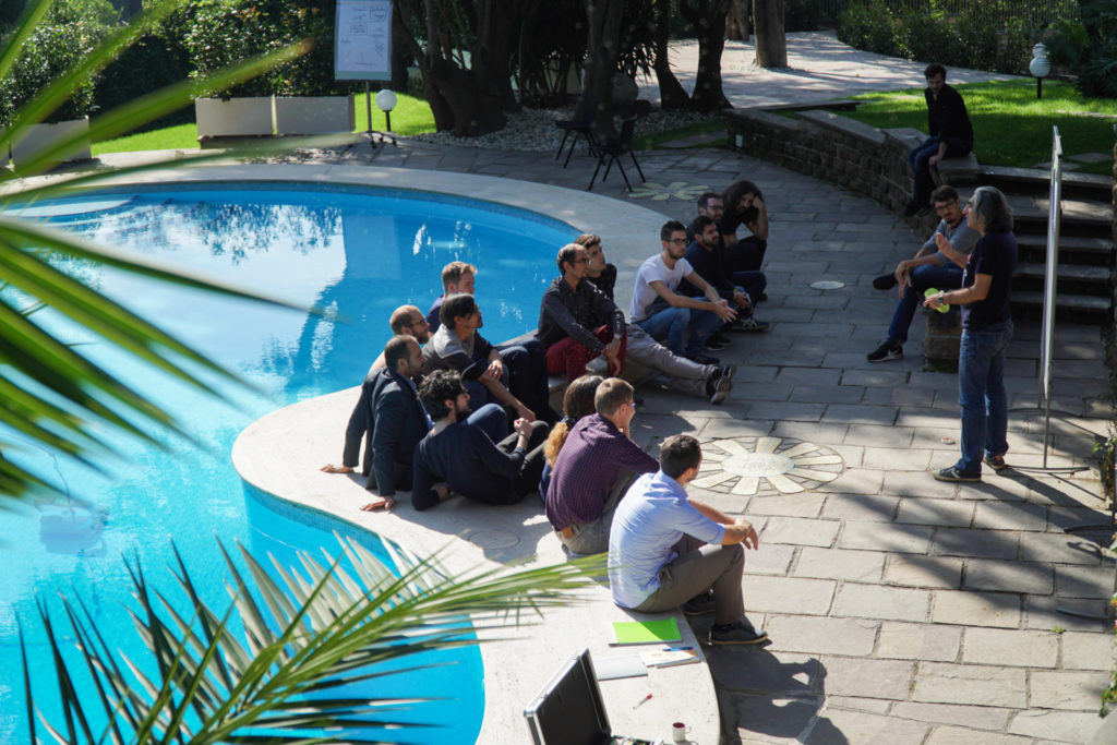 Participants listening to a lecture by the pool